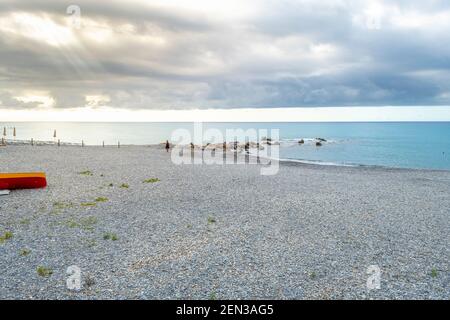 Ein einsamer Mann geht entlang der Küste und Strand in Ventimiglia, Italien, während die Sonne an der italienischen Riviera aufgeht. Stockfoto