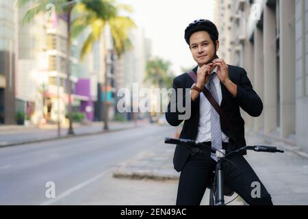 Asiatische Geschäftsmann in Anzügen tragen Sicherheitshelme auf Straßen der Stadt für ihren Morgen pendeln zur Arbeit Fahrrad. Umweltfreundlicher Transport. Stockfoto