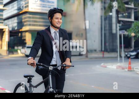 Asiatischer Geschäftsmann schiebt sein Fahrrad von zu Hause am Morgen Vorbereitung auf sein Fahrrad zur Arbeit zu fahren. Eco-Übertragung. Stockfoto
