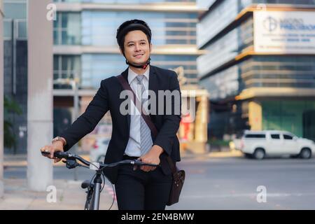 Asiatischer Geschäftsmann schiebt sein Fahrrad von zu Hause am Morgen Vorbereitung auf sein Fahrrad zur Arbeit zu fahren. Eco-Übertragung. Stockfoto