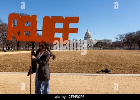 Washington, DC, USA, 25. Februar 2021. Im Bild: Ein Protestler hält den letzten Teil einer Sammlung von Zeichen, die Real People Real Relief bei einer Kundgebung für wirtschaftliche Anreize buchstabiert, mit dem US-Kapitol im Hintergrund. Demonstranten forderten den Kongress auf, regelmäßige Zahlungen an alle in den USA zu leisten und einen Weg zur Staatsbürgerschaft für nicht dokumentierte Bewohner zu schaffen. Kredit: Allison C Bailey/Alamy Live Nachrichten Stockfoto