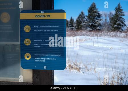 Ottawa, Ontario, Kanada - 25. Februar 2021: Ein COVID-19-Zeichen auf einem Pfad der National Capital Commission (NCC) legt Regeln während der Coronavirus-Pandemie fest. Stockfoto
