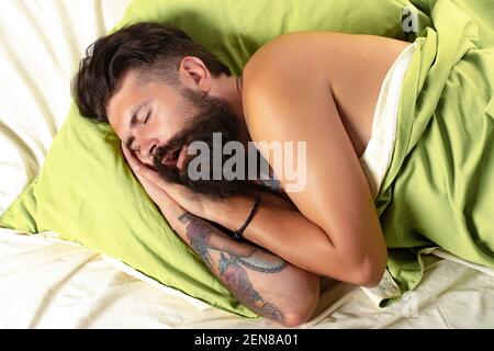 Mann im Bett versucht zu schlafen. Mann schläft im Schlafzimmer auf dem Bett liegend. Braucht etwas Ruhe. Stockfoto