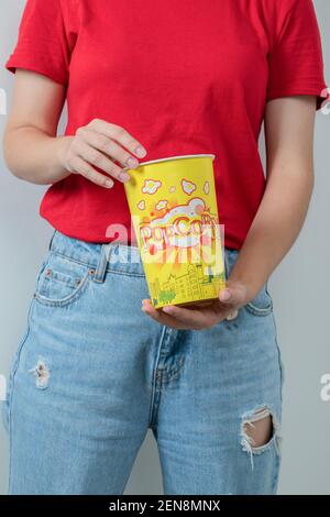 Junges Mädchen in rotem Hemd mit einer Schachtel Popcorns Stockfoto