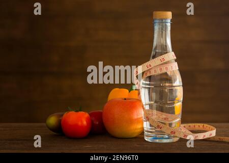 Wasser und Maßband mit Obst auf Holzboden. Gesundheit Lebensstil und Fitness-Konzept Stockfoto