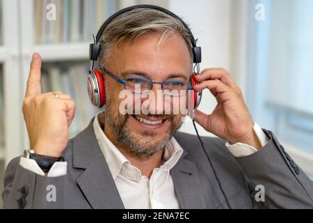 Erfolgreicher reifer Geschäftsmann sitzt am Office Desk, die Hand in Ja-Geste, feiert Geschäftserfolg. Lächelnd Aufgeregt Geschäftsmann Gesturing. Stockfoto