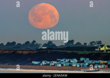 New Forest, Hampshire. 26th. Februar 2021. Wetter in Großbritannien. Der Mond geht über Strandhütten in Milford on Sea im New Forest unter. Der Vollmond im Februar, der als Schneemon bekannt ist, wird morgen um 8,18am Uhr in vollen Zügen erscheinen. An diesem Wochenende wird es kaum Schnee geben, mit einem hellen und sonnigen Wetter für die Südküste. Credit Stuart Martin/Alamy Live News Stockfoto