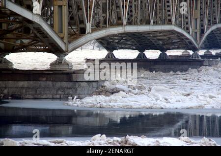 Die Eisscholle presst gegen die Stahlbrücke über den Fluss. Gefährliche Bedingungen im Winter. Stockfoto