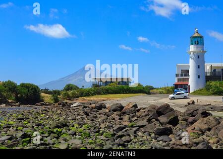 Historischer Cape Egmont Leuchtturm in der Taranaki Region, Neuseeland. Am Horizont ist der Berg Taranaki Stockfoto