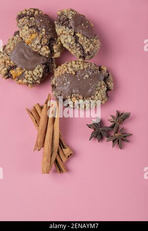 Schokoladen-Nüsse-Kekse auf einem rosa Hintergrund mit Zimtstangen Stockfoto