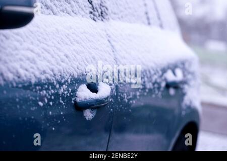 Ein Porträt der seitlichen Türgriffe eines Autos, das während eines Schneesturms völlig unter Schnee liegt. Das Fahrzeug ist komplett weiß und sollte freigeräumt werden Stockfoto