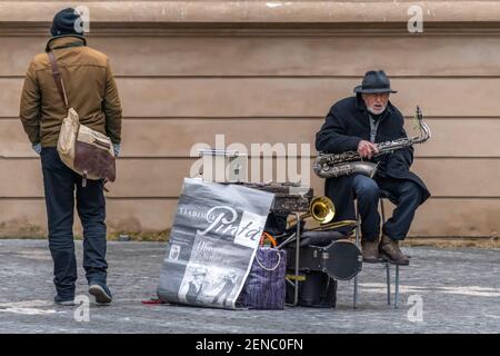 Prag, Tschechische Republik -19. Januar 2020: Alter Mann, Straßenmusiker mit Saxophonsitzen auf der Straße. Stockfoto