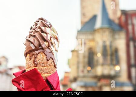 Weibliche Hand hält traditionelle tschechische Cookie trdelnik auf der Altstadt Hintergrund in Prag. Stockfoto