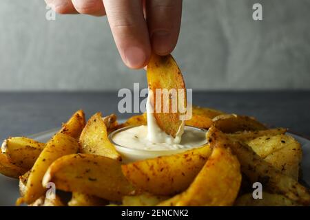 Weibliche Hand Dip Kartoffelkeil in Sauce, Nahaufnahme Stockfoto