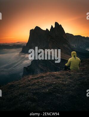 Mann, der im Sommer bei Sonnenuntergang auf dem Berggipfel relaxt Stockfoto