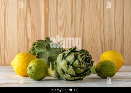 Reife Bio Artischocken auf einem weißen Holztisch mit Zitrone. Gemüsehintergrund. Stockfoto