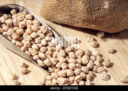 Ungekochte Kichererbsen auf Schaufel auf rustikalem Holztisch. Rustikales Stillleben Stockfoto