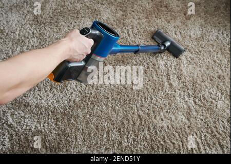 Hand halten modernen Staubsauger auf Teppich Hintergrund Stockfoto