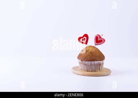 Hausgemachte Muffins mit herzförmigen Kerzen auf weißem Hintergrund. Feiertag und Valentinstag Geschenkkarte Hintergrund mit Kopierplatz. Stockfoto