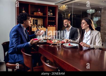Drei elegant gekleidete Geschäftsleute beim Abendessen und genießen ihre Freizeit Stockfoto