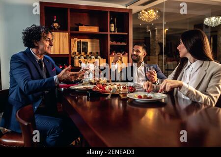Zwei Geschäftsleute und eine Geschäftsfrau beim Abendessen und einem Treffen Stockfoto