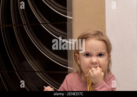 Nette kleine kaukasische Kind essen Pasta mit Händen mit wütend Gesicht Stockfoto