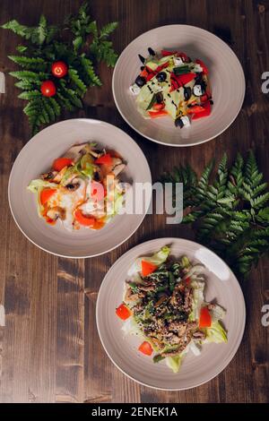 Set von Salaten auf dunklem Hintergrund. Griechischer Salat, Caesar Salat, Gemüsesalat Stockfoto