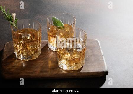 Drei Gläser Whiskey serviert auf Felsen mit Rosmarin, Zitronenschalen. Nahaufnahme. Stockfoto