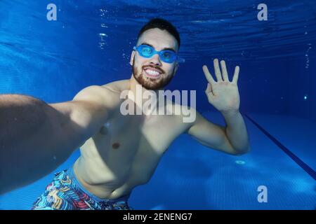 Hübscher junger Mann, der ein Unterwasser-Selfie im Schwimmen nimmt Pool Stockfoto