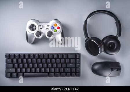 Konzept für Gaming- und Gamer-Geräte. Gamer Arbeitstisch Raum Hintergrund, Draufsicht. Tastatur, Maus, Gamepad Joystick, Mauspad und Kopfhörer. Auf grau ta Stockfoto