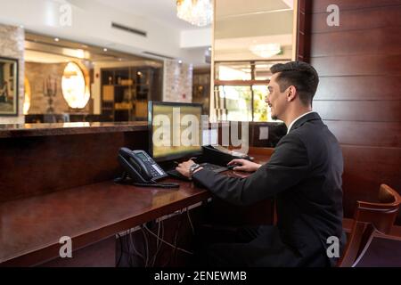 An der Rezeption arbeitete der Rezeptionist, während er auf dem Stuhl saß Stockfoto