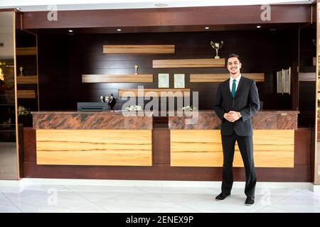 Rezeptionist steht vor dem Empfangstresen, Hotelmanagement-Konzept Stockfoto