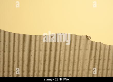 Braune Wellpappe mit abgerissenen Kanten auf gelbem Hintergrund, Kopierraum Stockfoto