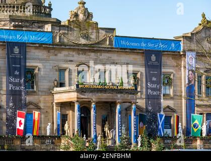 East Lothian, Schottland, Vereinigtes Königreich, 26th. Februar 2021. Princess Switch Drehort: Das Gosford House verwandelt sich in das Montenaro Royal Museum für einen Weihnachtsfilm des dritten Teils der romantischen Netflix-Komödie mit Vanessa Hudgens, Kränzen an den Fenstern, Weihnachtsbäumen und Dekorationen sowie Vorbereitungen für gefälschten Schnee. Die Banner und internationalen Flaggen deuten auf ein internationales Friedensereignis in der Handlung hin Stockfoto