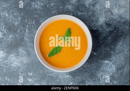 Blick von oben auf die frische, hausgemachte Tomatensuppe in einer weißen Schüssel Auf grauem Hintergrund Stockfoto