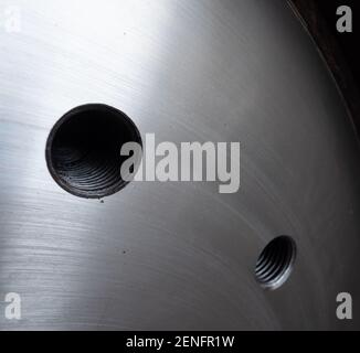 Edelstahlplatte mit Gewindebohrungen für Schrauben. Geringe Schärfentiefe mit dem nächstgelegenen Loch im Fokus. Stockfoto