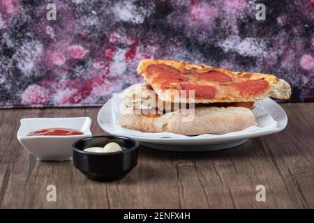 Frische Pepperoni Pizzascheiben auf weißem Teller mit Sauce Stockfoto