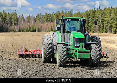 John Deere 7430 Traktor vor dem Egge Pflug auf kultiviertem Feld an einem schönen Tag des Frühlings. Salo, Finnland. 13.Mai 2017. Stockfoto