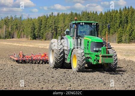 John Deere 7430 Traktor vor Egge Pflug auf dem Feld an einem schönen Tag des Frühlings. Salo, Finnland. 13.Mai 2017. Stockfoto