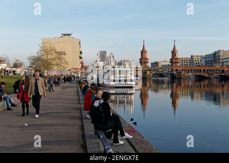 Vorfruehling in Berlin Mitte Februar 2021 , Spreeufer bei der East Side Gallery , Spaziergaenger, Promenade, Hostel Boat, Stockfoto