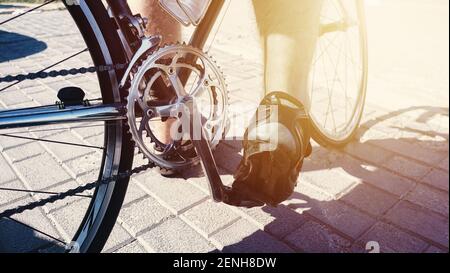 Radler Fuß auf einem professionellen Sportfahrrad. Nahaufnahme der Fahrradkette. Detail der Fahrrad-Metall-Komponenten - Kette, hintere Kassette, Umwerfer, b Stockfoto