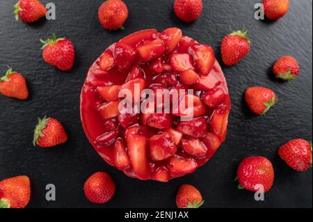 Käsekuchen mit Erdbeere und frischen Beeren auf schwarzem Hintergrund Stockfoto