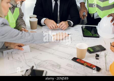 Architekten, Ingenieure und Designer, sitzen am Tisch, analysieren Blaupausen Stockfoto