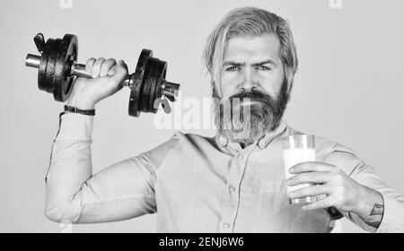 Vitamine für Muskeln. Sportlerinnen halten Hanteln und Glas Milch. Proteindiät. Proteincocktail. Quelle des Kalziums. Bärtiger Mann trinkt Milch. Trainieren Sie im Fitnessstudio. Milch gute Nährstoffe. Fettmenge. Stockfoto