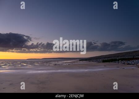 Westward Ho! Strand in der Abenddämmerung weitläufiger Sandstrand mit Sonnenuntergang Himmel. Stockfoto