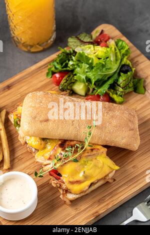 Gegrilltes Hähnchen- und Cheddar-Sandwich mit pommes Frites und Salat. Stockfoto