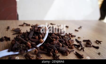 Indische getrocknete Nelken Gewürz auf Holztisch Hintergrund. Trockene aromatische Blütenknospen, Blüten in einem Löffel. Indische köstliche Gewürznelken Stockfoto