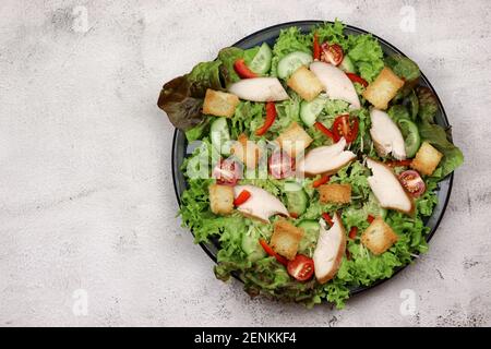 Caesar Salat mit Kirschtomaten auf einem Teller auf hellem Hintergrund. Draufsicht, flach liegend Stockfoto