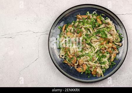 Reisnudeln mit Austernpilzen, Gurken und Huhn auf einem Teller auf hellem Hintergrund. Draufsicht, flach liegend Stockfoto