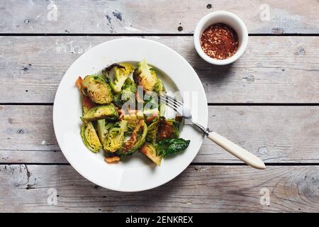 Geröstete Rosenkohl mit Speck auf Holzhintergrund, Draufsicht. Stockfoto